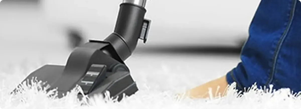Close-up of a professional vacuuming a white carpet in Mission.