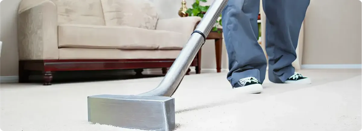 Carpet cleaning technician using a hot-water extraction wand on a light-colored carpet in a living room, Kansas City, MO.